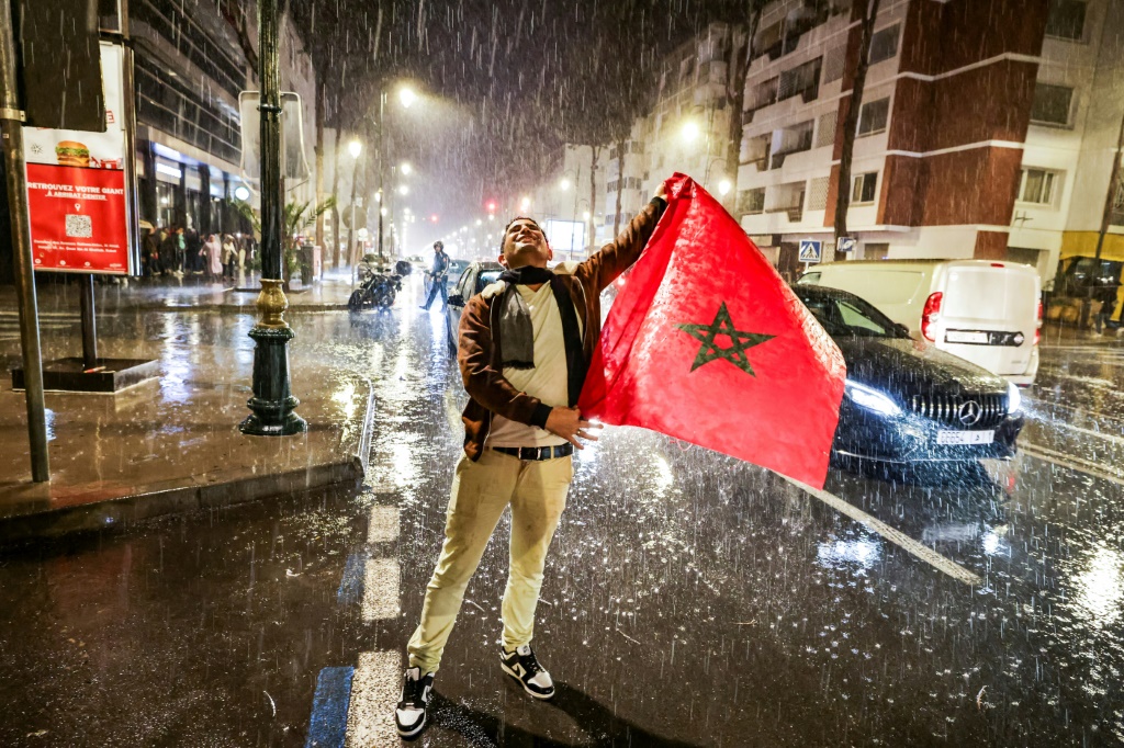 Un supporter marocain tient le drapeau du Maroc sous la pluie lors de la demi-finale de la Coupe du monde de football 2022 France-Maroc