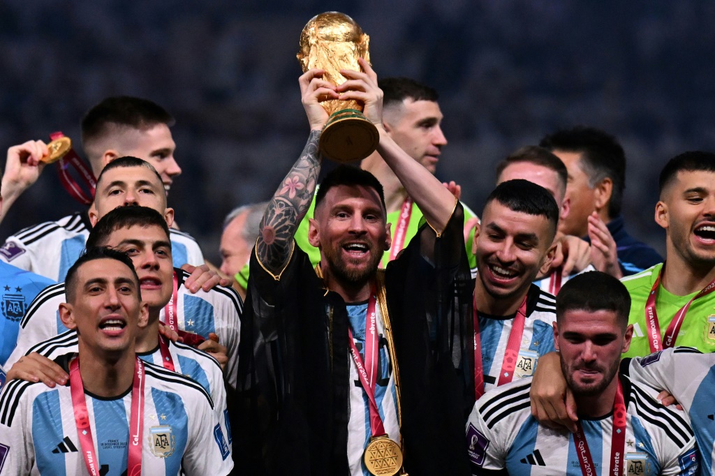 Le joueur argentin Lionel Messi entouré de ses coéquipiers soulève la Coupe du monde de football remportée dimanche 18 décembre 2022 par l'Argentine face à la France aux tirs aux but au stade Lusail au Qatar.