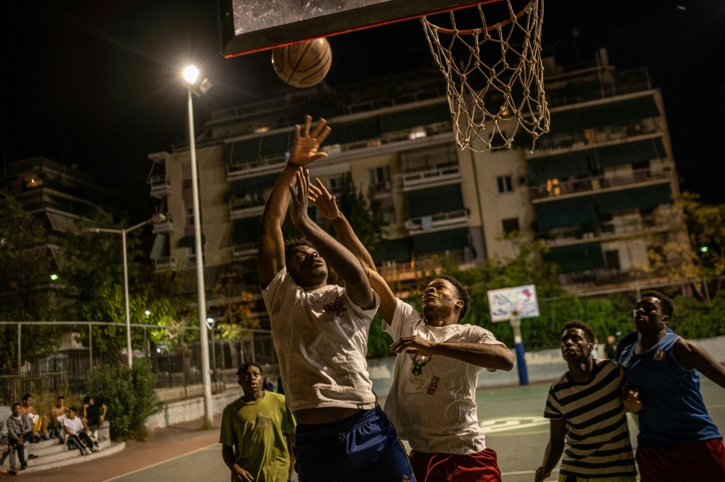 De jeunes basketteurs afro-grecs jouent sur un terrain à Athènes