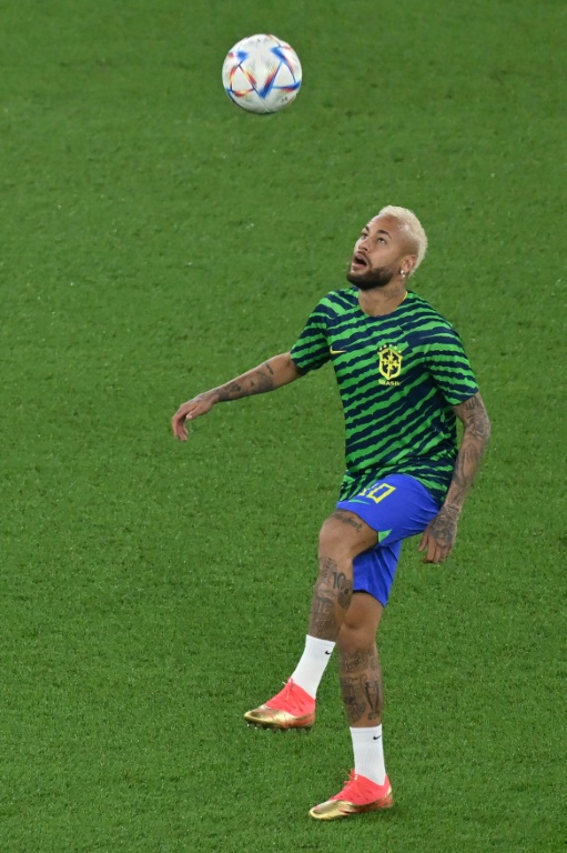 Le joueur brésilien Neymar est ausculté par un médecin sur le terrain du match opposant le Brésil à la Serbie lors du Mondial-2022, le 24 novembre 2022 à Doha (Qatar)