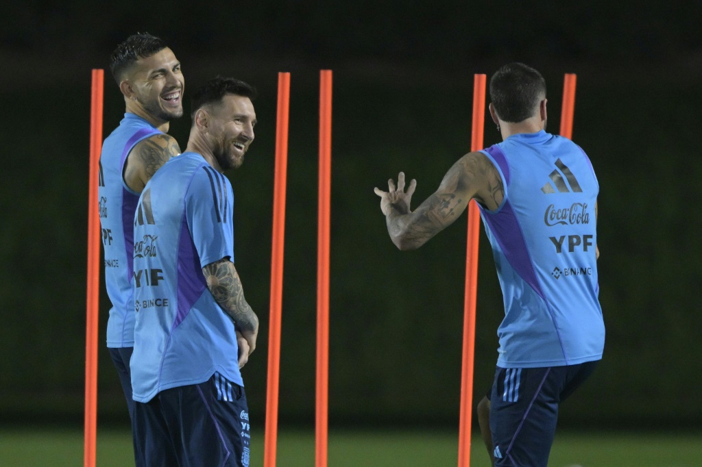 L'attaquant argentin Lionel Messi (C) plaisante avec ses coéquipiers Rodrigo De Paul (D) et Leandro Paredes (G) lors d'un entraînement le 5 décembre 2022 à Doha avant le 1/4 de finale du Mondial face aux Pays-Bas