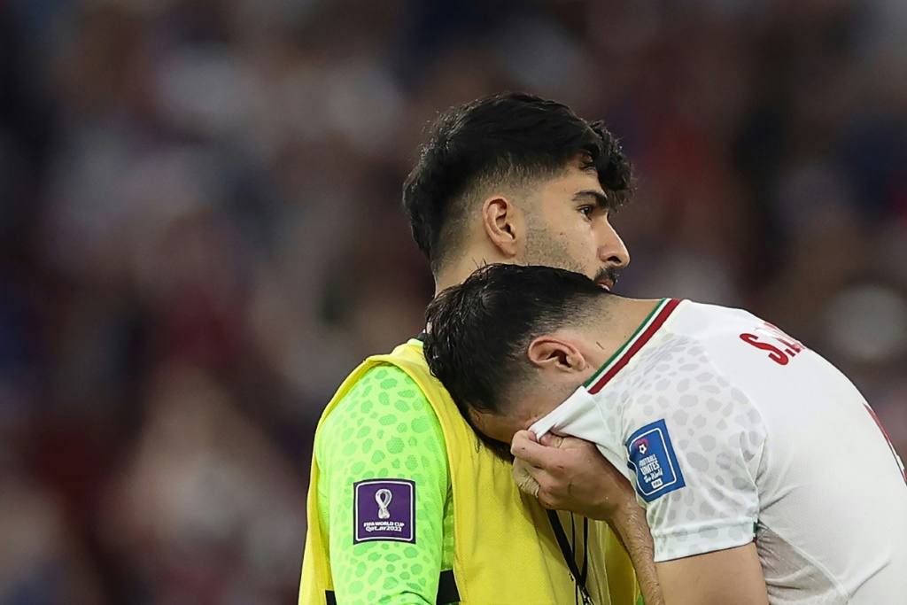 Le milieu de terrain Saeid Ezatolahi pleure sur l'épaule de son gardin Amir Abedzadeh après la défaite de l'Iran contre les Etats-Unis au Mondial synonyme d'élimination le 29 novembre 2022 au stade al-Thumama à Doha