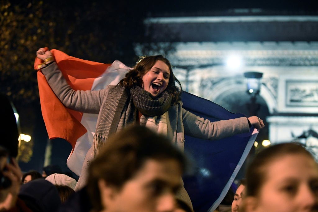 Une supportrice de la France célèbre la victoire contre le Maroc en demi-finale du Mondial-2022 de football, le 14 décembre 2022 à Paris sur les Champs-Elysées