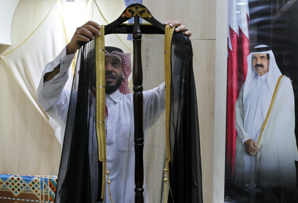 Un employé expose un manteau traditionnel qatari (bisht) fabriqué dans le souk Waqif de Doha, le 20 décembre 2022