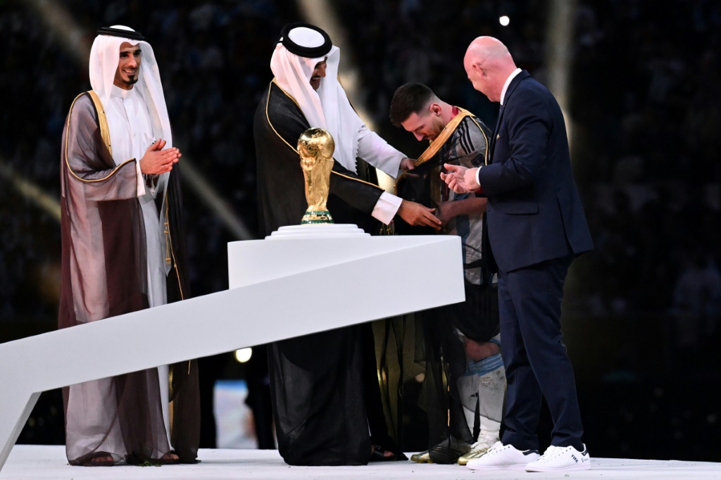 L'émir du Qatar Cheikh Tamim bin Hamad al-Thani couvre Lionel Messi du désormais célèbre manteau traditionnel arabe avant la remise du trophée du Mondial, le 18 décembre 2022 à Doha