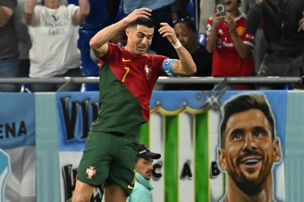 Le Portugais Cristiano Ronaldo célèbre son but avec en fond une bannière montrant l'Argentin Lionel Messi pendant le match du Mondial-2022 entre le Portugais et le Ghana au stade 974 à Doha, le 24 novembre 2022