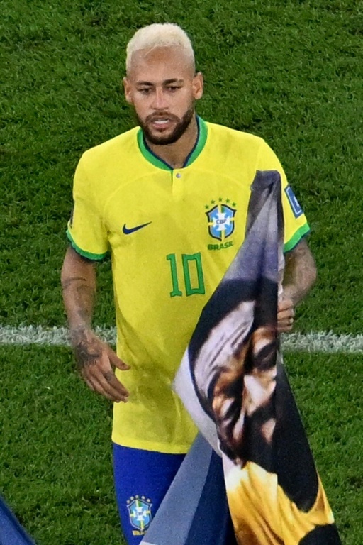 La star brésilienne Neymar porte une affiche de Pelé à la fin d'un match de la coupe du monde au Qatar, le 5 décembre 2022