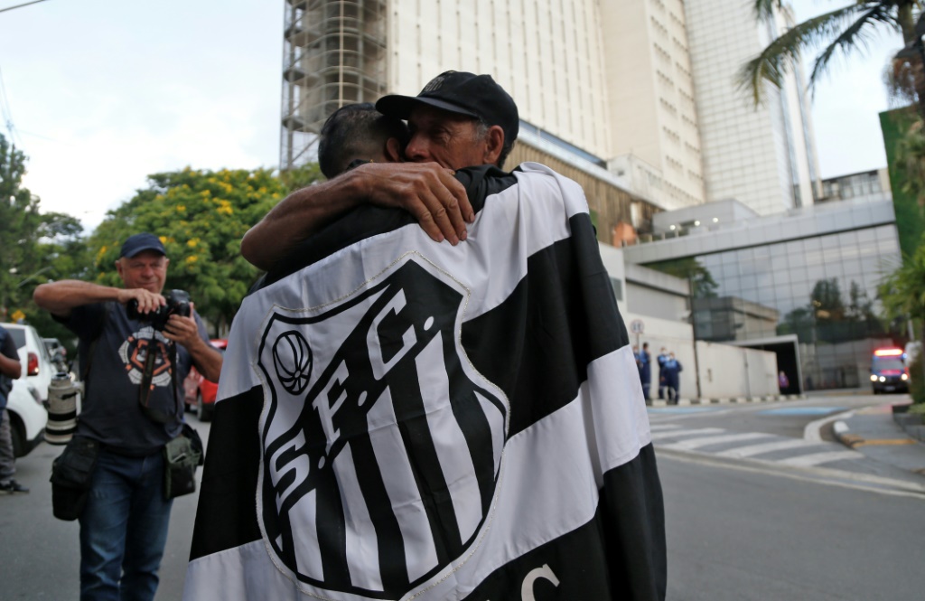 Un fan de la légende du football brésilien Pelé enveloppé dans un drapeau de l'équipe brésilienne Santos embrasse un autre fan devant l'hôpital Albert Einstein, où Pelé est décédé, à Sao Paulo, au Brésil, le 29 décembre 2022