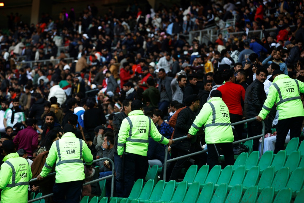 Des gardes de sécurité surveillent les supporteurs au stade de Bassora avant la finale de la Coupe du Golfe de football