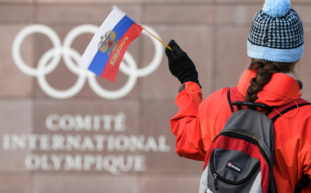 Une jeune femme brandit un drapeau russe devant le siège du Comité international olympique (CIO)