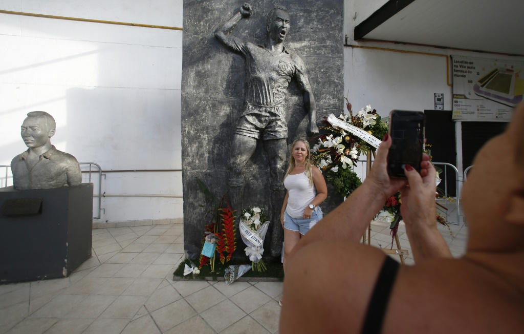 Une personne pose devant une sculpture de la légende brésilienne du football Pelé au stade Vila Belmiro de Santos (Brésil), le 1er janvier 2023