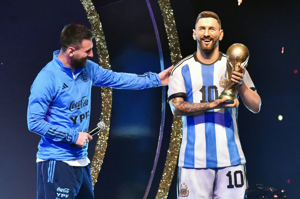 L'attaquant argentin Lionel Messi regarde une statue de lui-même lors d'un hommage rendu par la Conmebol aux membres de l'équipe nationale argentine sacrée à la Coupe du monde 2022 au Qatar