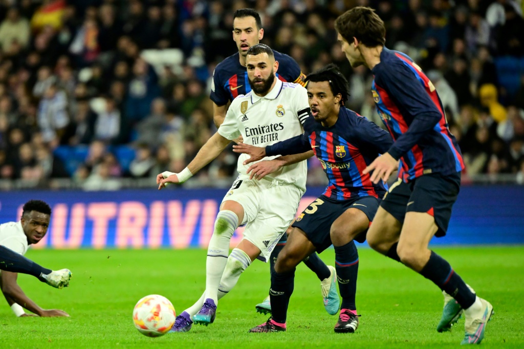 L'attaquant du Real Karim Benzema (g) marqué par le défenseur de Barcelone Jules Koundé (c)
