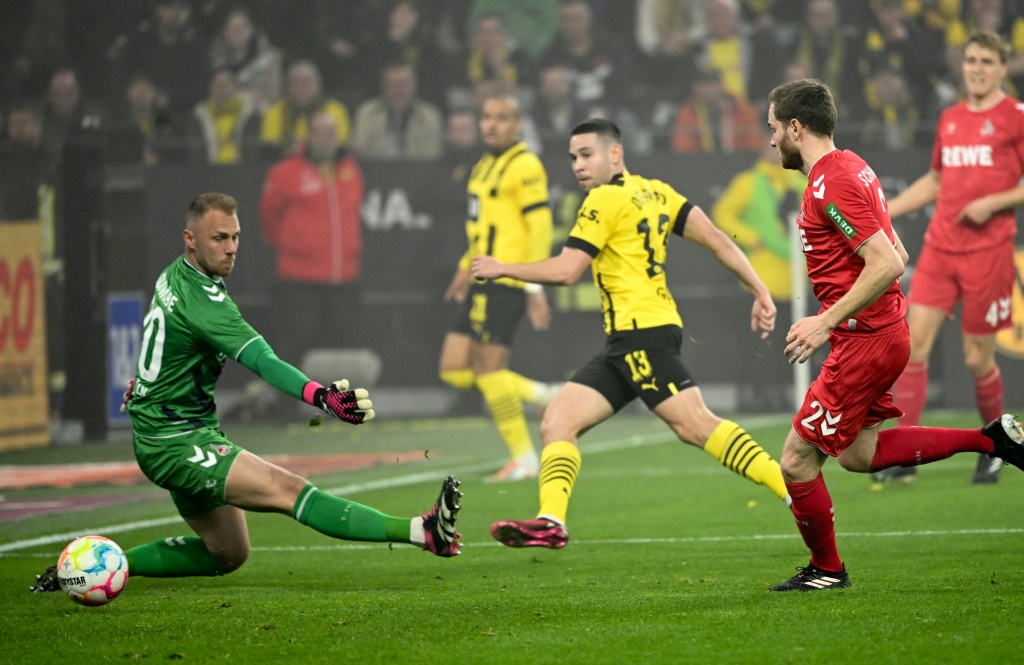 Le défenseur de Dortmund Raphaël Guerreiro (c) trompe le gardien de Cologne Marvin Schwaebe (g), le 18 mars 2023 à Dortmund
