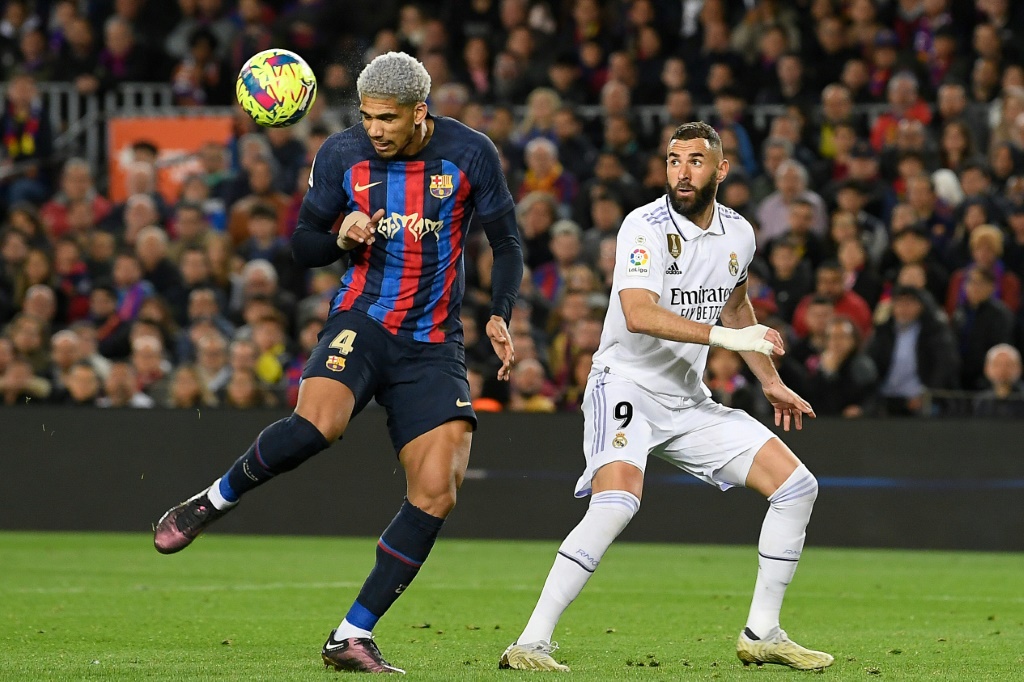Le défenseur de Barcelone Ronald Araujo (g) devant le capitaine du Real Karim Benzema, le 19 mars 2023 au Camp Nou