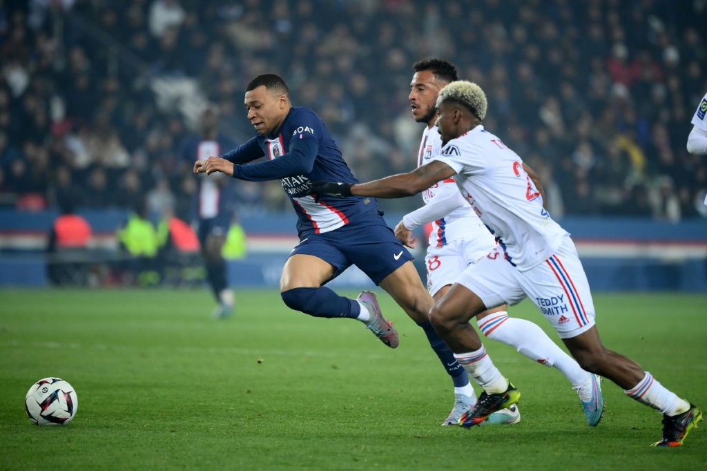 L'attaquant du PSG Kylian Mbappé devance le Lyonnais Thiago Mendes, le 2 avril 2023 au Parc des Princes