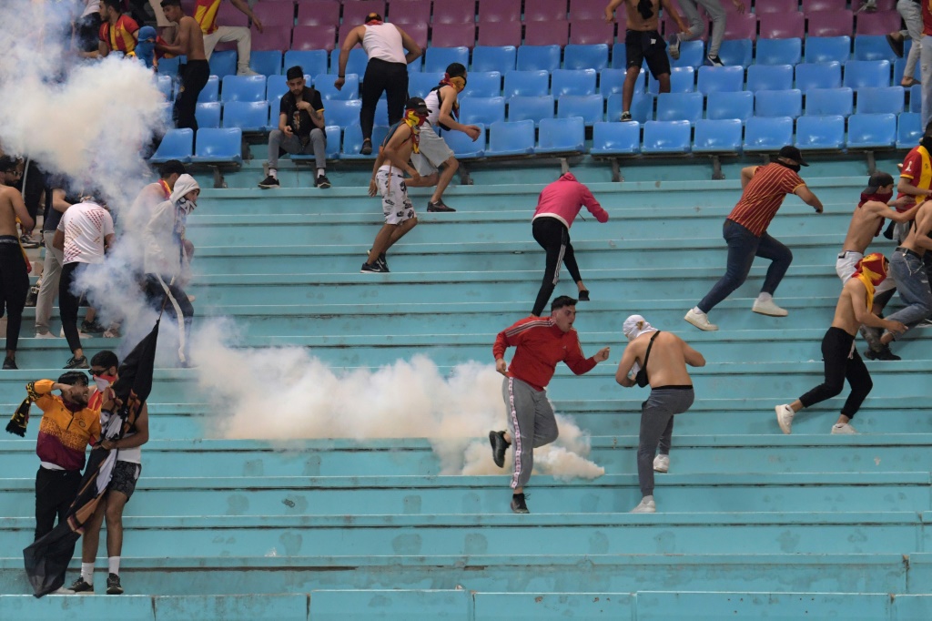 Des supporters de l'Espérance Tunis le 29 avril 2023 fuient des tirs de grenades lacrymogènes lancées par les forces de l'ordre
